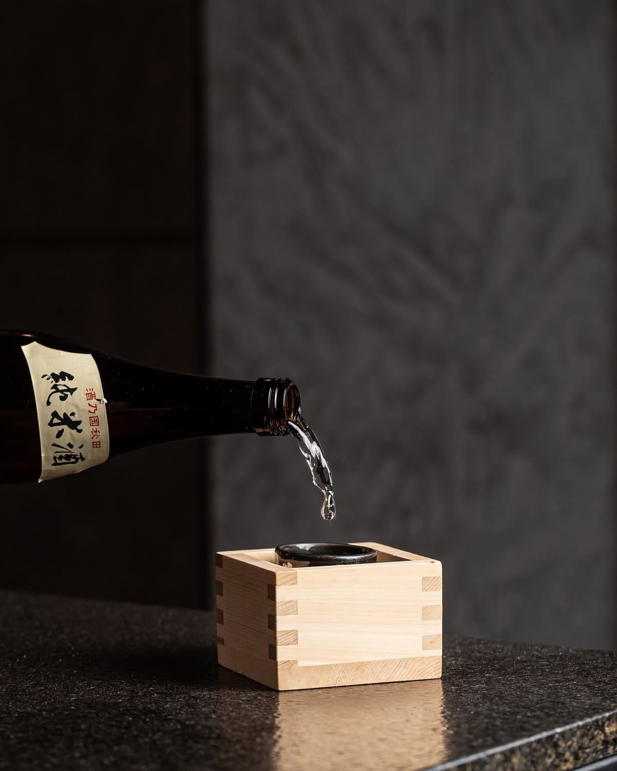 Saké versé dans un verre posé dans un masu traditionnel